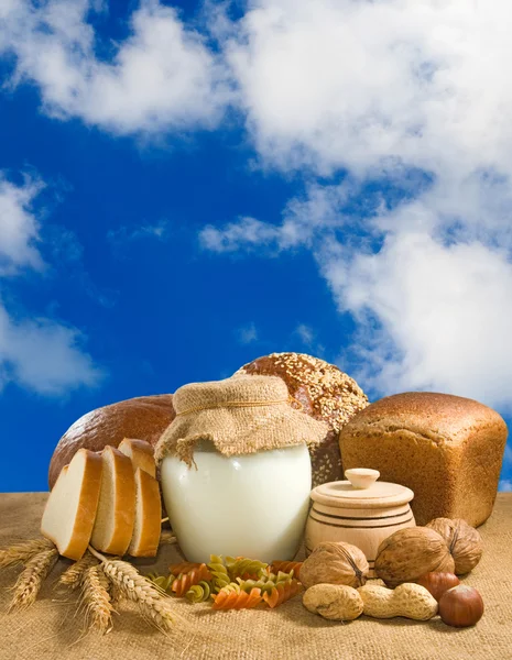 Mage of bread, nuts, wheat and dairy in the sky background close up