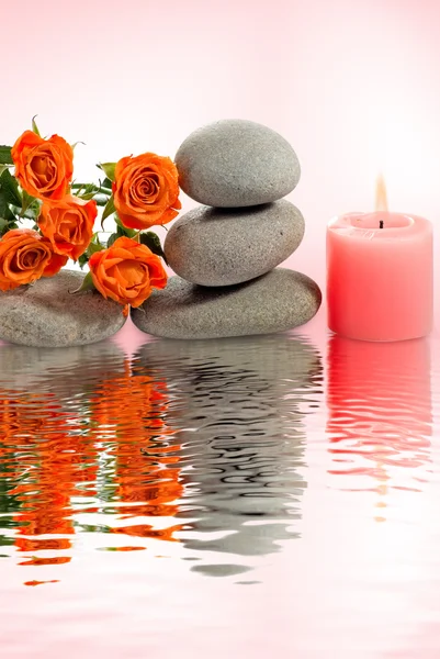 Image of stones, flower and candle above the water