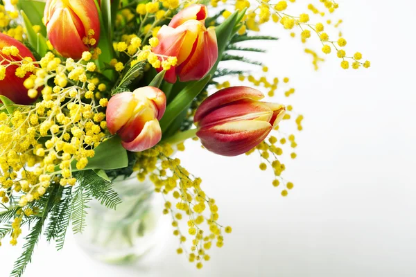 Bright spring bouquet of tulips and mimosa flowers on white