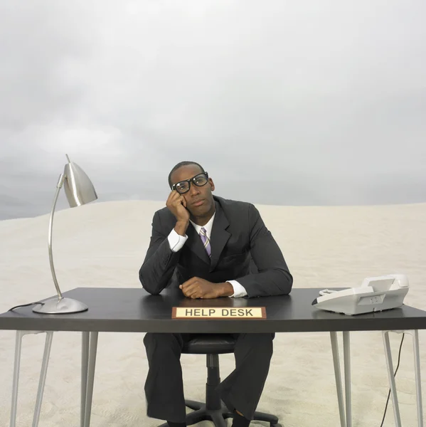 African businessman sitting at help desk in the desert