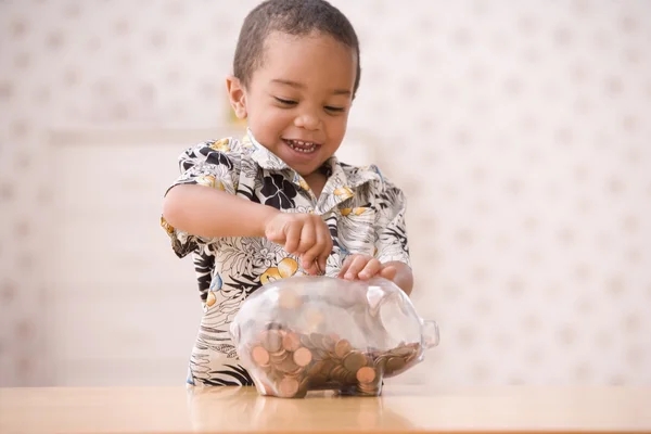 Young boy putting money in piggy bank