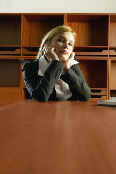 Businesswoman sitting at conference table leaning chin in hands