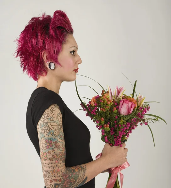 Woman with tattoos holding bouquet of flowers
