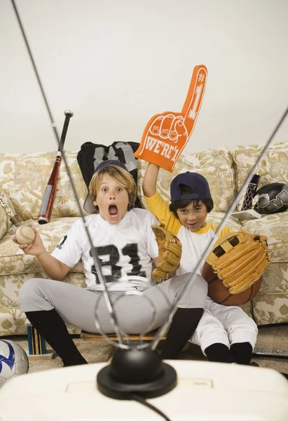 Two boys in sports gear watching television