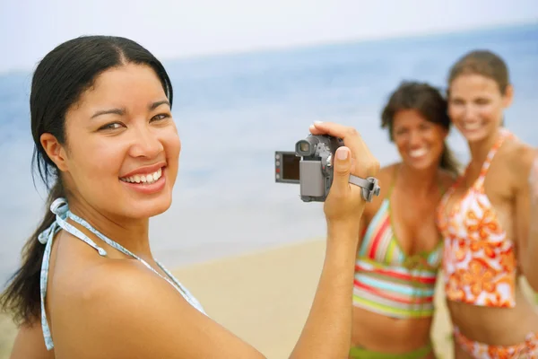 Woman video recording friends at beach