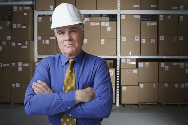 Businessman wearing hard hat in warehouse