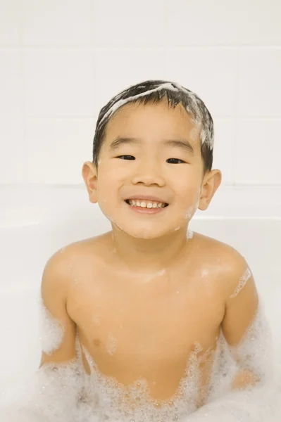 Young Asian boy smiling in bubble bath
