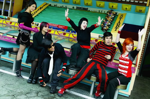 Group of punk Hispanic teenagers cheering in carnival booth