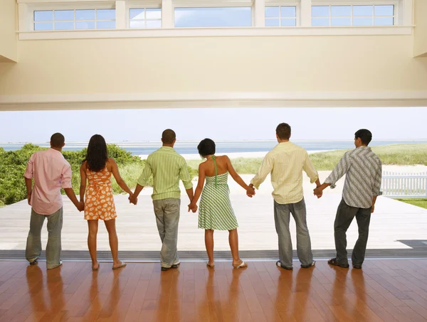 Multi-ethnic friends holding hands at beach resort