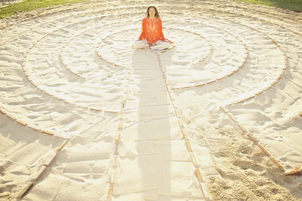 Woman sitting cross-legged in the middle of a meditation labyrinth