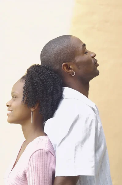 Young African couple standing back to back