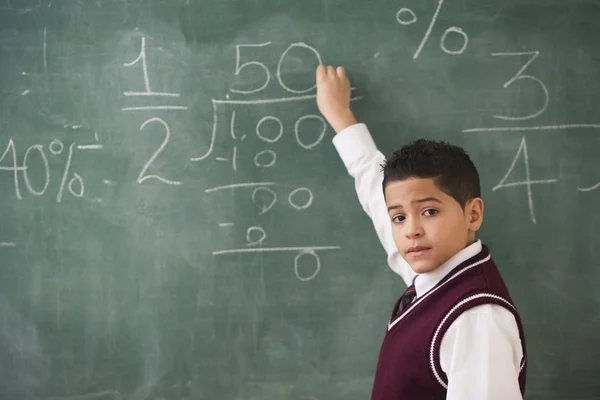 Young boy doing mathematics on the chalkboard