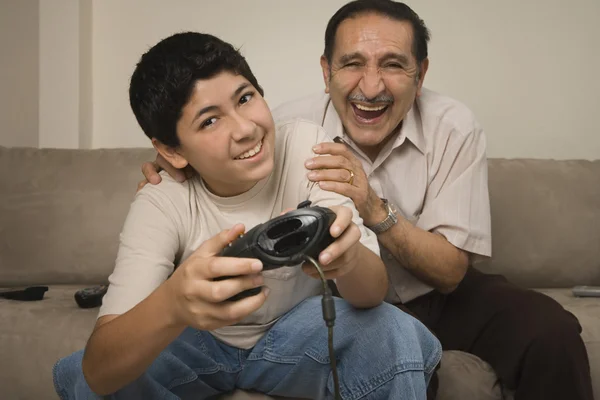 Hispanic grandfather laughing while grandson plays video game