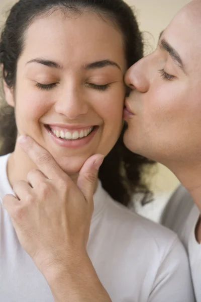 Hispanic man kissing Hispanic woman\'s cheek