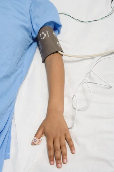 African child's arm with blood pressure cuff in hospital bed