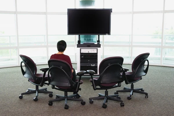 Woman sitting in chair in front of big screen TV