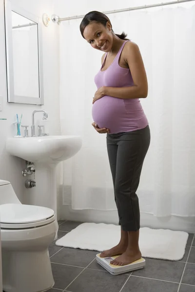 Pregnant African woman standing on scale
