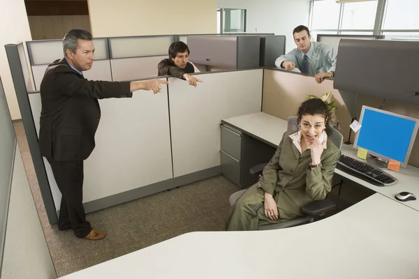 Businesspeople pointing at co-worker in office cubicle