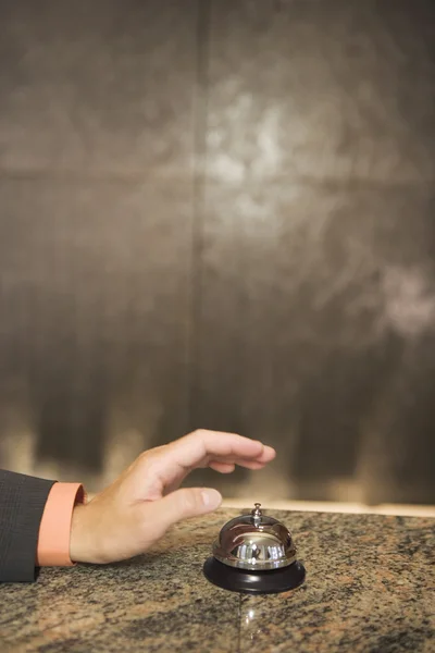 Hand reaching for service bell on counter