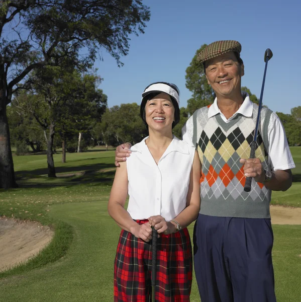 Senior Asian couple smiling on golf course