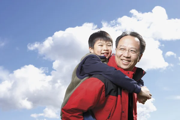 Asian father giving son piggyback ride outdoors