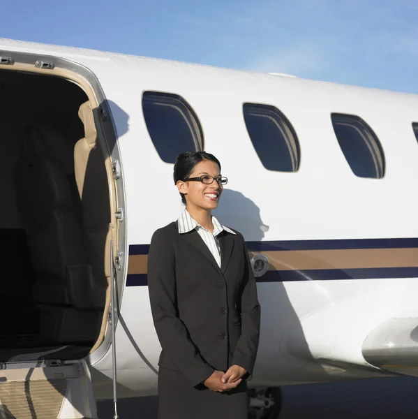 Female flight attendant standing next to airplane