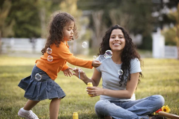 Mother and daughter blowing bubbles outdoors