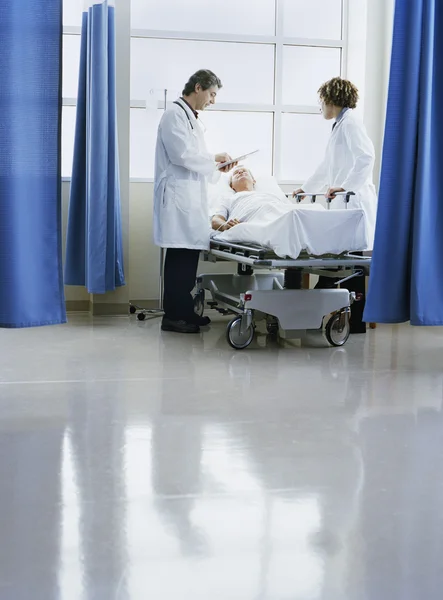 Doctors talking to patient in bed