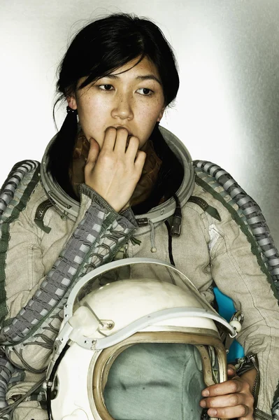 Female astronaut holding a helmet biting her finger nails