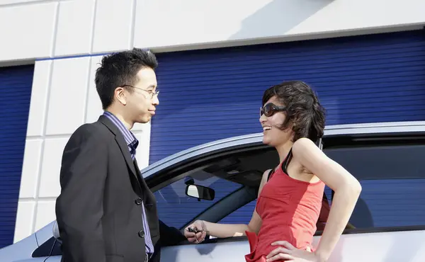 Asian businessman talking to woman next to car