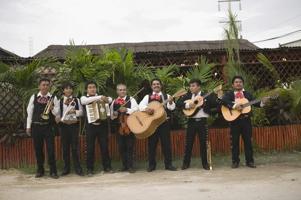 Mariachi band in front of building playing their instruments