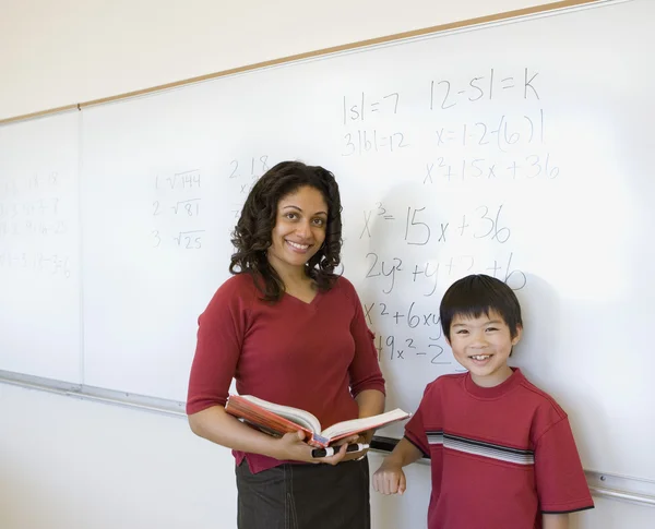 Female teacher with student in front of whiteboard
