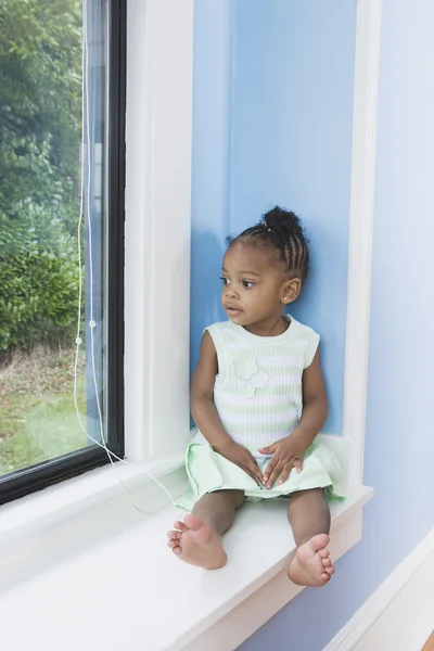 Young African girl sitting in window seat