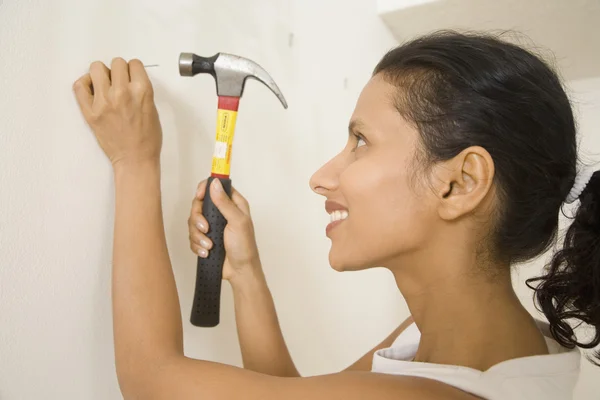 Indian woman hammering nail into wall