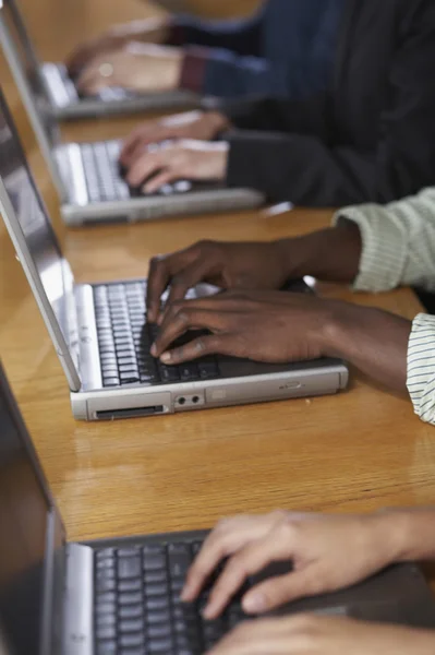 Multi-ethnic people typing on laptops