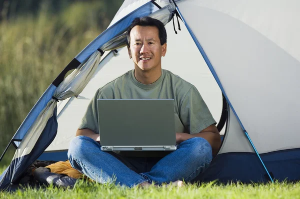 Man on laptop outside of tent