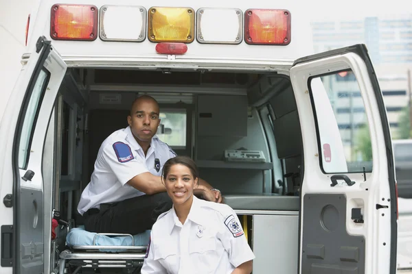 African female and male EMTs in ambulance