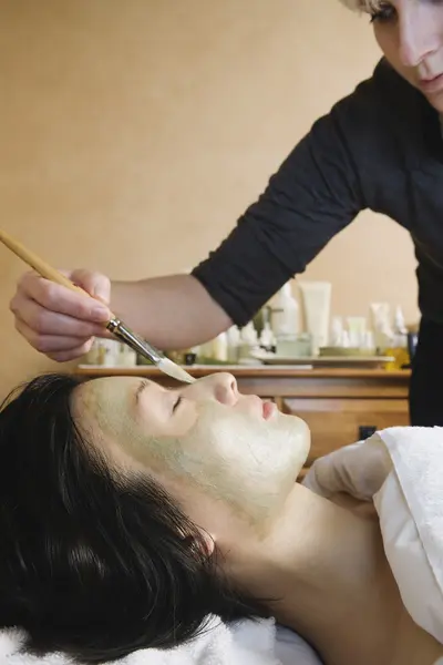 Asian woman receiving spa facial treatment