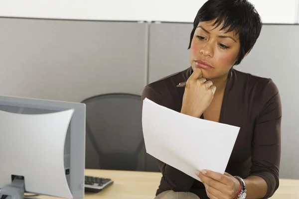Businesswoman reading papers at desk