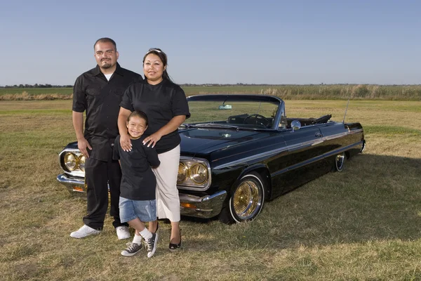 Hispanic family in front of low rider car