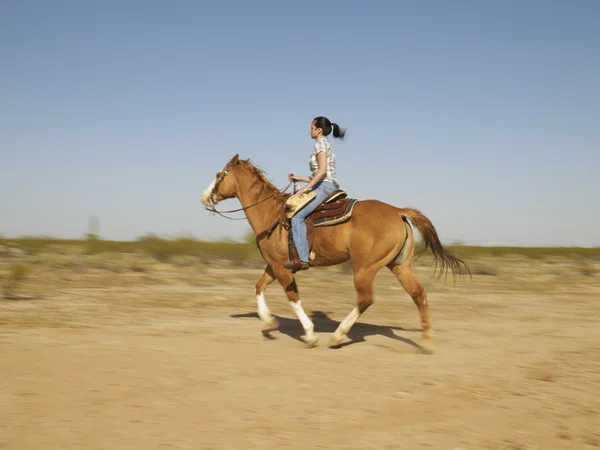 Hispanic woman riding horse