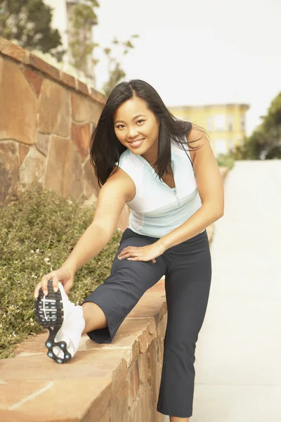 Asian woman in running gear stretching