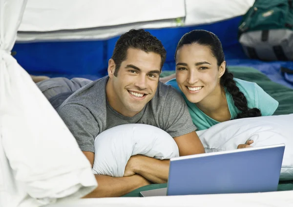 Hispanic couple with laptop in tent