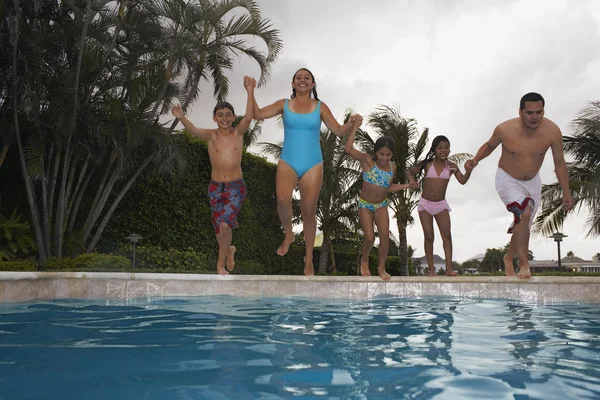 Multi-ethnic family jumping into swimming pool