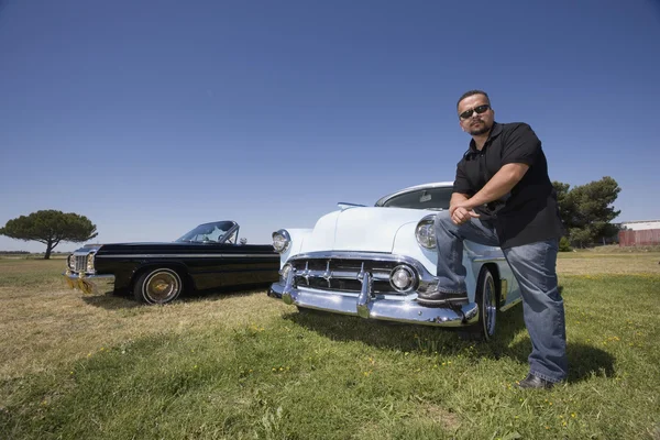 Hispanic man leaning on low rider car