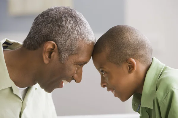 African American grandfather and grandson touching foreheads