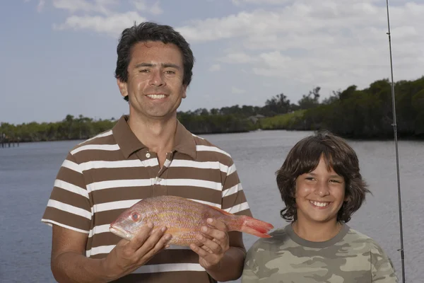 Hispanic father and son with freshly caught fish