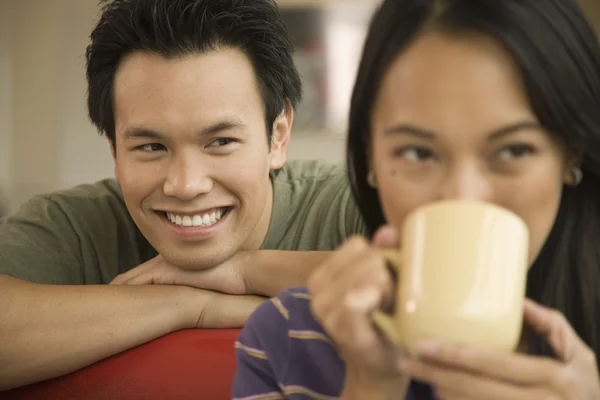 Asian man watching woman drink coffee
