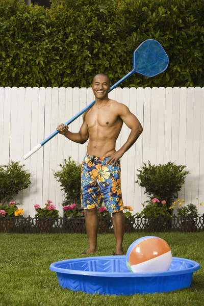 Mixed Race man holding net next to kiddie pool