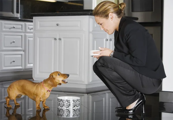 Hispanic businesswoman feeding dog